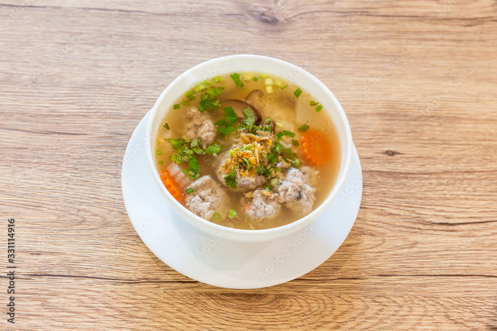 Boiled rice with pork in a white cup placed on a wooden table Boiled rice with pork in a white cup placed on a wooden table