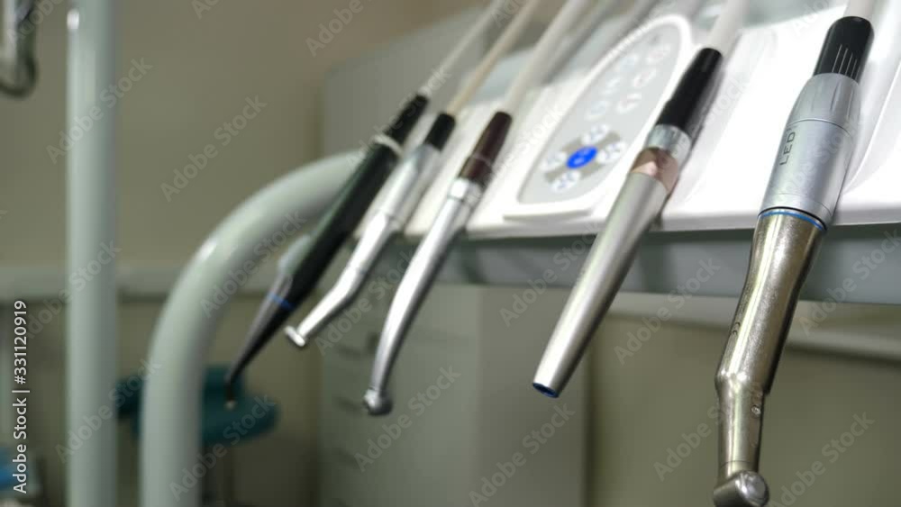Dental clinic: room with dental medical equipment on console. Hand in black glove moving Set of drills placed on dental instrument panel. Close-up. Tools for dental care. Office, Tools, Instruments Dental clinic: room with dental medical equipment on console. Hand in black glove moving Set of drills placed on dental instrument panel. Close-up. Tools for dental care. Office, Tools, Instruments