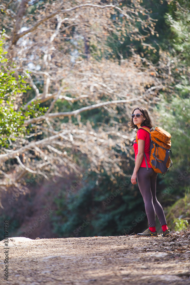 Obraz premium A girl with a backpack goes along a mountain trail.