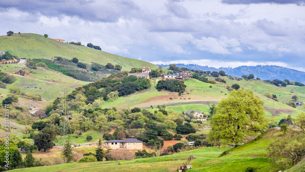 Spring landscape on the hills of south San Francisco bay area; scattered houses built on the slopes; San Jose, Santa Clara county, California