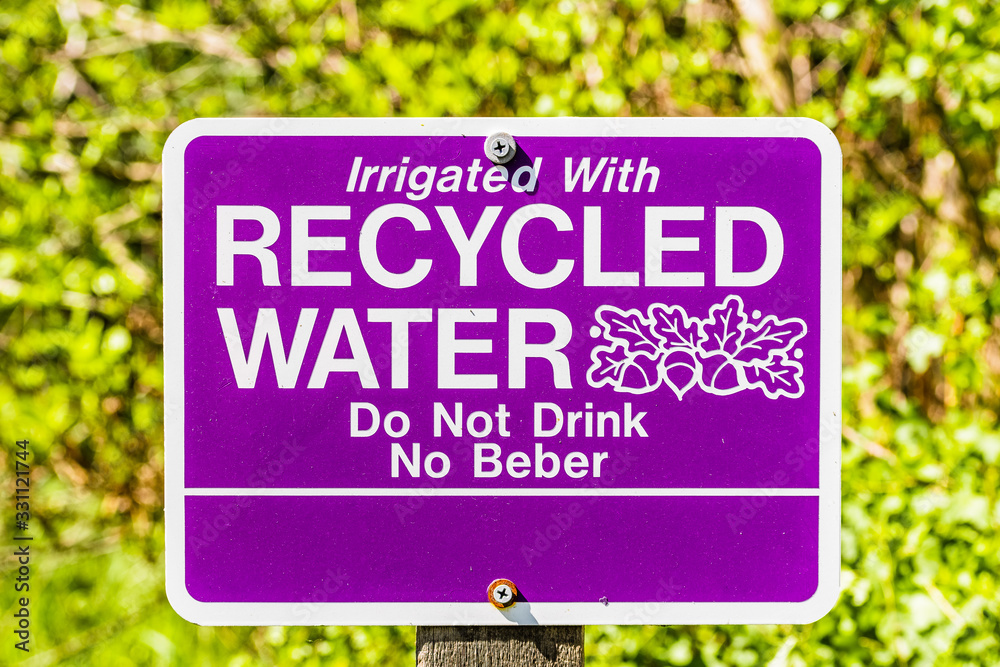 Close up of Irrigated with Recycled Water; Do Not Drink sign posted in a public park in Santa Clara, South San Francisco Bay Area, California