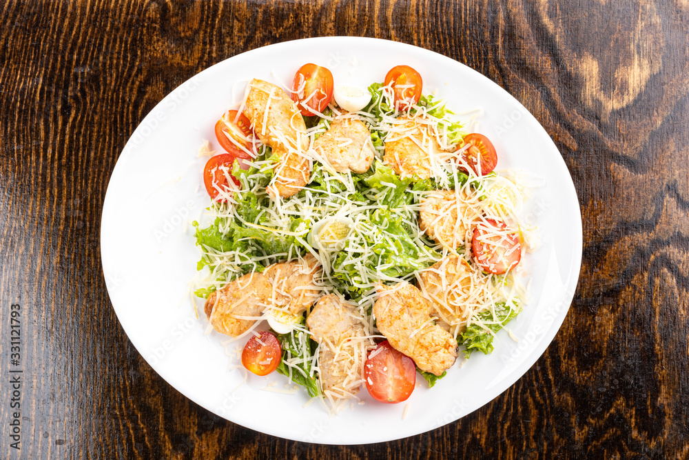 salad with meat, cheese, vegetables, mayonnaise, herbs on a white plate with a spoon on a wooden background salad with meat, cheese, vegetables, mayonnaise, herbs on a white plate with a spoon on a wooden background