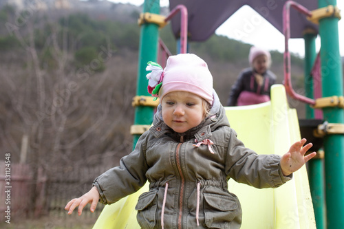 A little girl walk on a playground in an eco park against the background of a spring forest,