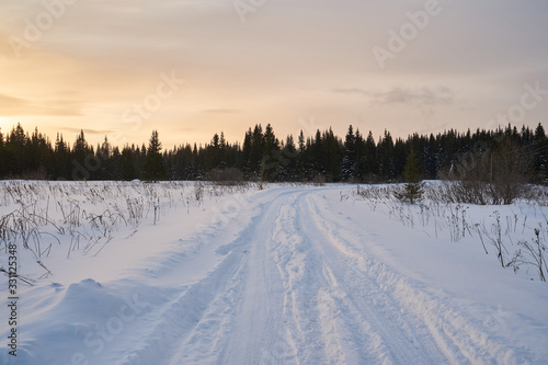  Snow- covered lake at dawn with boats on the shore. Winter forest with snow-covered fir trees high in the mountains. Sunny February day in the spruce forest. 