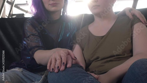 Two lesbians on the couch hugging. A girl with colored hair and a bald woman hold hands. Free same-sex love. Homosexual relationship. LGBT Community Pride Concept