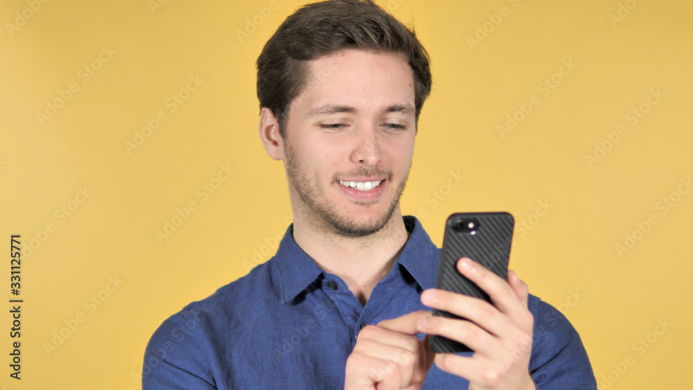 Casual Young Man Using Smartphone on Yellow Background