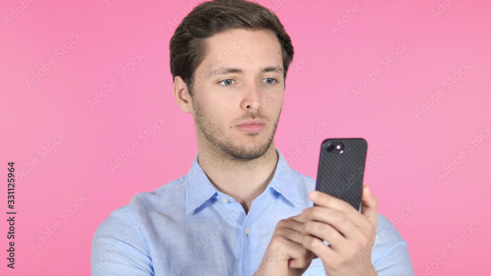 Young Man Using Smartphone on Pink Background Young Man Using Smartphone on Pink Background