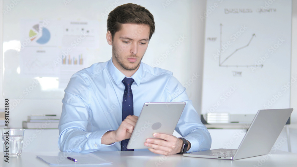 Young Businessman Using Tablet in Office Young Businessman Using Tablet in Office