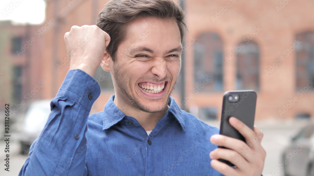 Outdoor Portrait of Young Man Excited for Success on Smartphone Outdoor Portrait of Young Man Excited for Success on Smartphone
