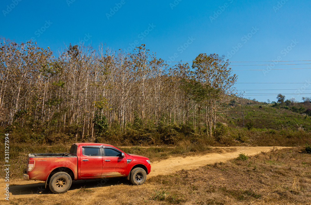 Red 4x4 truck, dirty with dust, on dirt road in the middle of nowhere in rural outback area.