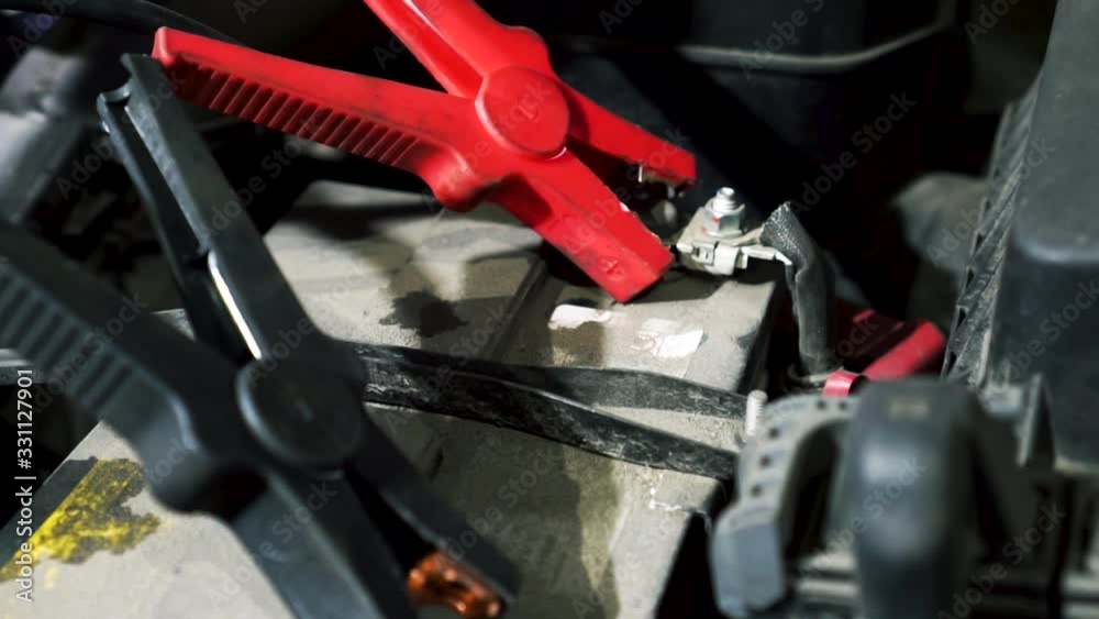 Close up of charging car battery with electricity trough cables at the car service. Footage. Concept of repair, professional electric equipment. Close up of charging car battery with electricity trough cables at the car service. Footage. Concept of repair, professional electric equipment.