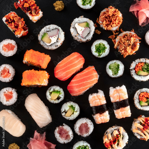 Large sushi set, overhead square close-up shot on a black background. An assortment of various maki, nigiri and rolls