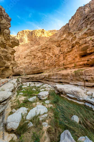 Wadi Shab river canyon with rocky cliffs and green water springs - Sultanate of Oman