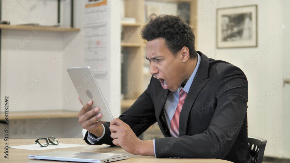 Shocked Young African Businessman Using Tablet