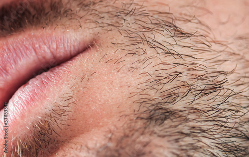 young man's chin skin texture covered with hair and beard bristles of different color and length