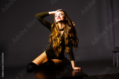 Beautiful dancer. Girl model. the girl sits in a hat and sits on a table. girl in a beautiful underwear. the girl is sitting on the table and fooling around, making faces. smooth, well-groomed legs