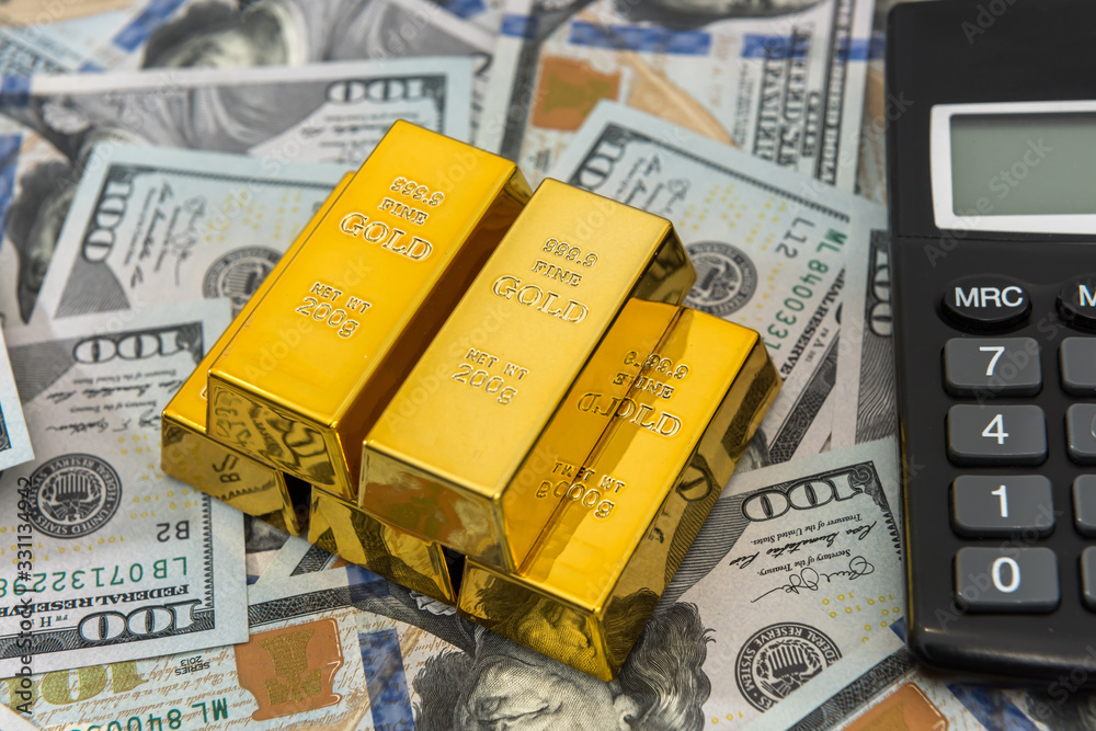 Gold bars with calculator lying on dollar bills background. Save money concept Gold bars with calculator lying on dollar bills background. Save money concept