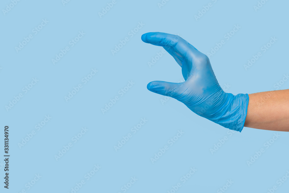 Doctor's hand in a blue medical glove holds an object on a blue background. infection control. mocap, you can insert your product for advertising Doctor's hand in a blue medical glove holds an object on a blue background. infection control. mocap, you can insert your product for advertising