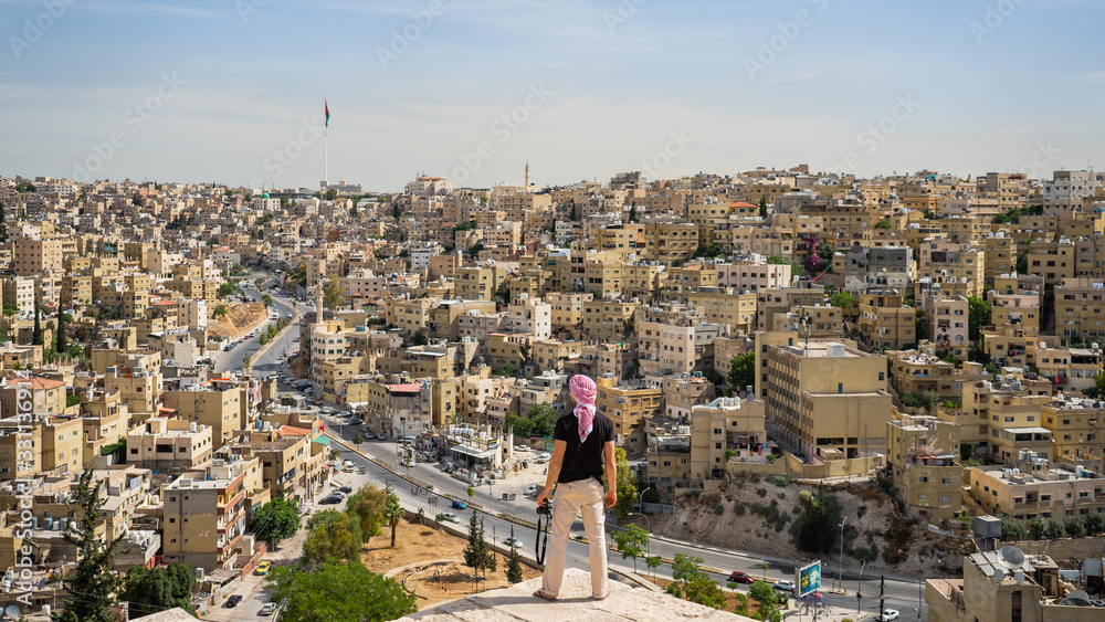 Fototapeta premium Young man enjoying the view of the city from Amman Citadel or Jabal al-Qal'aa, a historic site from the Neolithic period in the heart of downtown Amman in Jordan in the Middle East. Travel concept