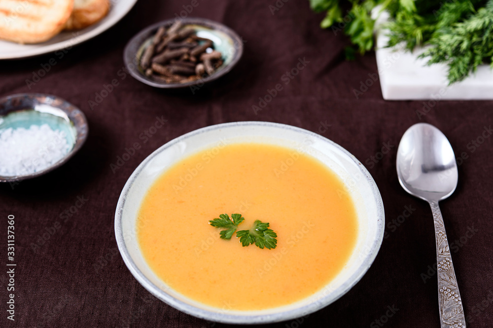Healthy Vegetable Cream Soup in a bowl with toast grill on linen tablecloth. Vertical composition. Selective focus Healthy Vegetable Cream Soup in a bowl with toast grill on linen tablecloth. Vertical composition. Selective focus