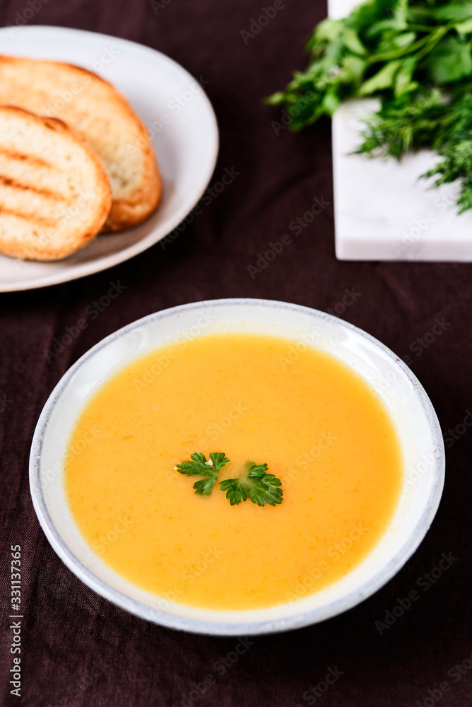 Healthy Vegetable Cream Soup in a bowl with toast grill on linen tablecloth. Vertical composition. Selective focus Healthy Vegetable Cream Soup in a bowl with toast grill on linen tablecloth. Vertical composition. Selective focus