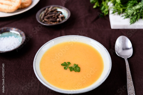 Healthy Vegetable Cream Soup in a bowl with toast grill on linen tablecloth. Vertical composition. Selective focus