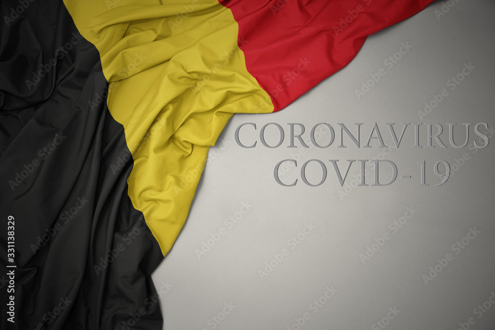 waving national flag of belgium on a gray background with text coronavirus covid-19 . concept.