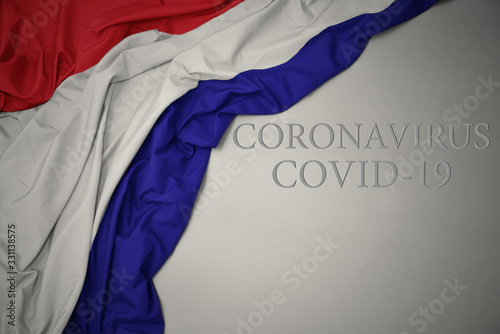 waving national flag of netherlands on a gray background with text coronavirus covid-19 . concept.