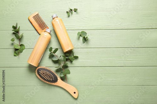 Shampoo with herbal extract, comb and brush on wooden background