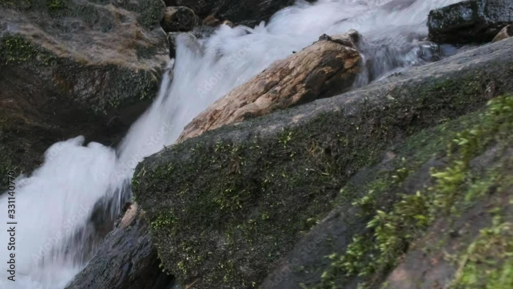 Shallow depth of field, dolly side shot of water flowing in springtime down a rapid stream with moss covered rocks Shallow depth of field, dolly side shot of water flowing in springtime down a rapid stream with moss covered rocks