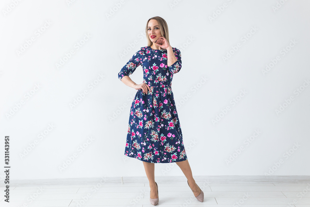 Fashionable young blonde woman in beautiful summer dress posing at white studio with copy space. Fashionable young blonde woman in beautiful summer dress posing at white studio with copy space.