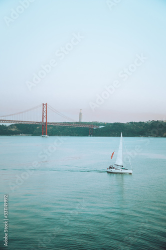 Sailboat sailing in the sea near Lisbon in the evening sunlight. Luxury summer adventure.