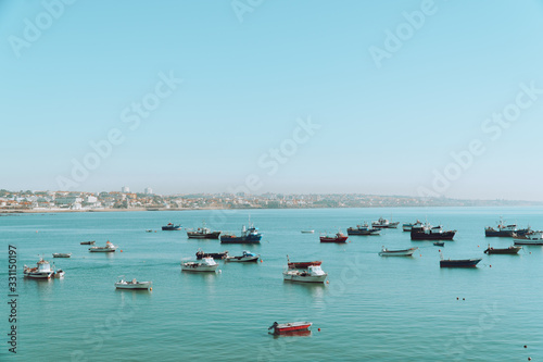 Boats are anchored in the middle of the sea in open water near the city on a sunny day. Transportation and travel.