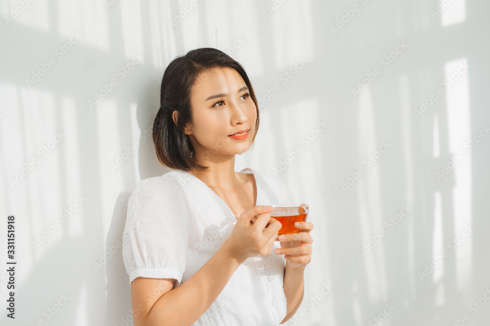 Happy woman thinking and looking at side beside a window at home Happy woman thinking and looking at side beside a window at home