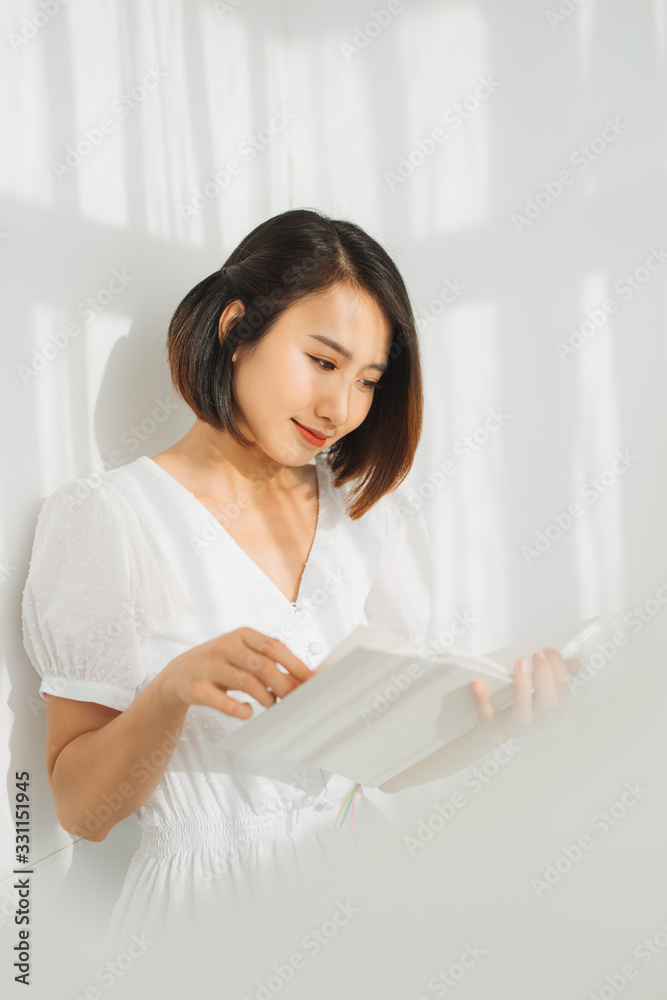 Young woman reading a book while relaxing at home with sunlight. Young woman reading a book while relaxing at home with sunlight.
