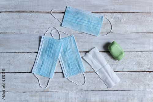 Blue disposable medicine masks, soap, spitit napkin  on white wooden background photo