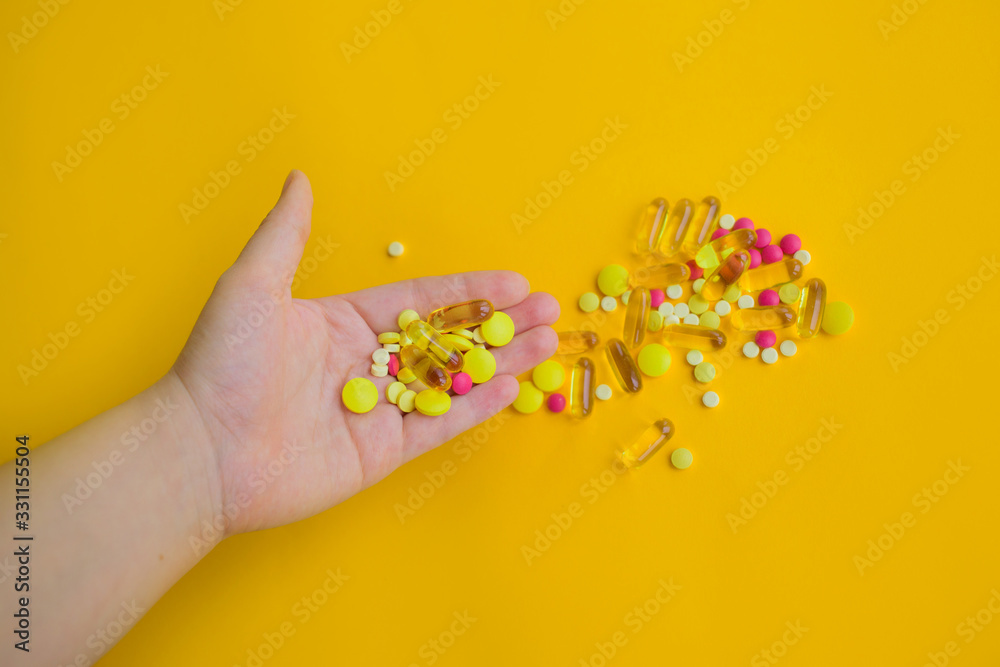 Tablets, pills and capsules on yellow background. Copy space.