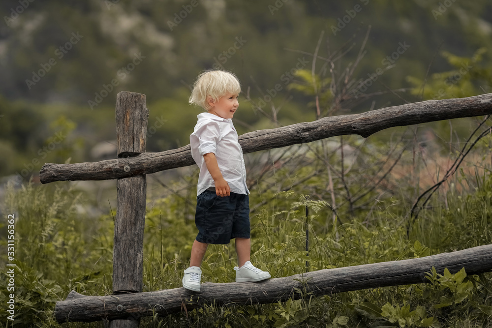 A 4-year-old child climbs a wooden old fence.