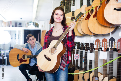 Teenagers examining guitars in shop