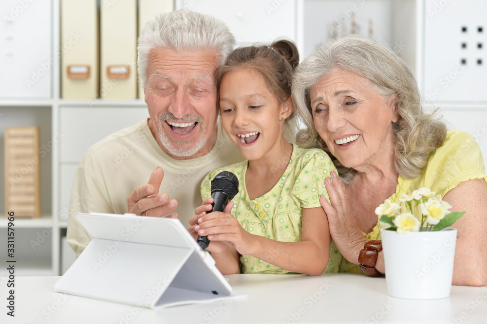 Portrait ofgrandparents with granddaughter singing karaoke Portrait ofgrandparents with granddaughter singing karaoke
