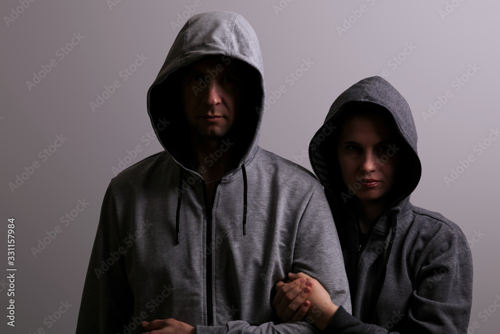 Man and woman in hoods stand by, low key