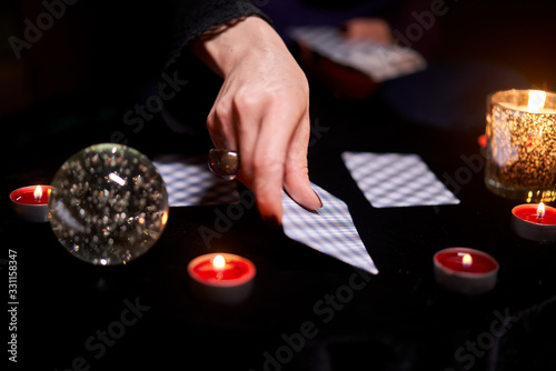 Fortuneteller woman divines on cards sitting at table with candles
