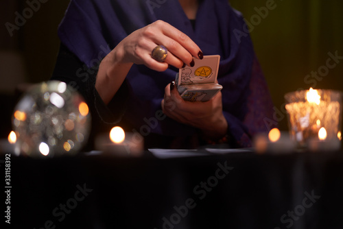 Fortuneteller female divines on cards at table with candles