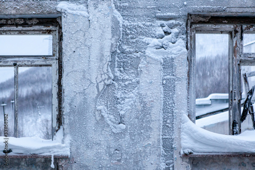 Old concrete wall with broken windows. Abandoned district. Russian far North © Kateryna