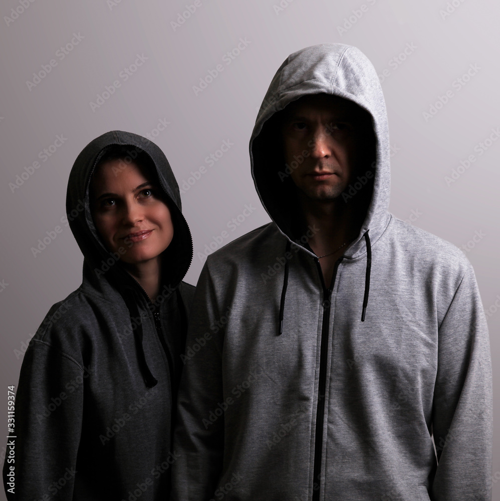 Man and woman in hoods stand by, low key Man and woman in hoods stand by, low key