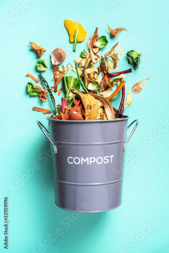 Fotografi Peeled vegetables in white compost bin on blue background
