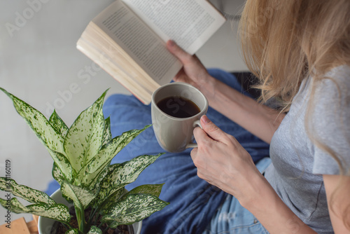 Woman reading a book and drinking tea.