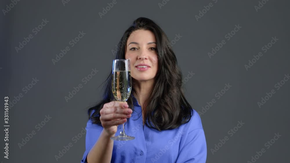 Attractive latin mature woman smiling and holding glass of champagne or wine on grey studio background. Drinking alcohol concept Attractive latin mature woman smiling and holding glass of champagne or wine on grey studio background. Drinking alcohol concept