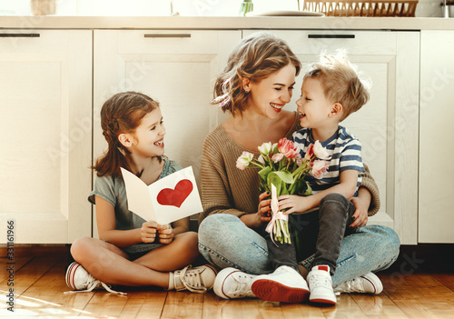 Little children congratulating mother in kitchen.