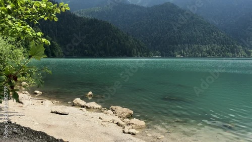 Beautiful mountain lake Ritsa. Clean lake Ritsa in Abkhazia. Lake among the mountains overgrown with trees, view from the shore. photo